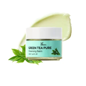 A jar of Xiran Green Tea Pure Cleansing Balm alongside a smear of the balm and green tea leaves.